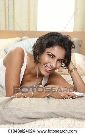 Young woman listening to music on bed View Large Photo Image Picture - Young woman listening to music on bed. Fotosearch