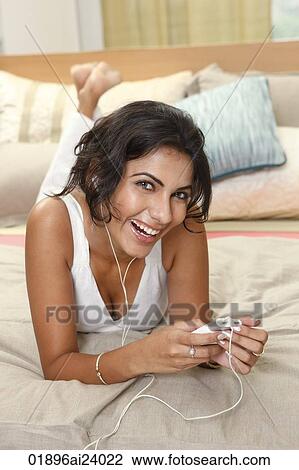Young woman listening to music on bed View Large Photo Image Stock Image - Young woman listening to music on bed. Fotosearch