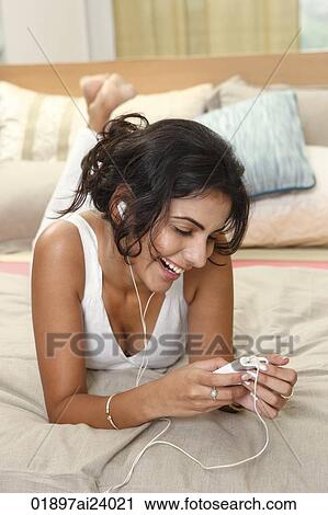 Young woman listening to music on bed View Large Photo Image Stock Image - Young woman listening to music on bed. Fotosearch