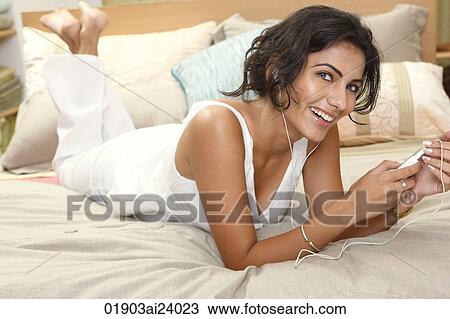 Young woman listening to music on bed View Large Photo Image Stock Image - Young woman listening to music on bed. Fotosearch