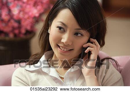 Stock Image - Young woman using mobile phone. Fotosearch