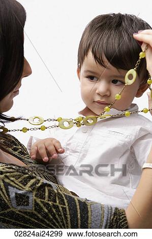 Stock Photo - baby in mother's arms, playing with necklace. Fotosearch