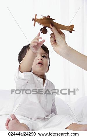 Stock Image - boy boy reaching for toy airplane. Fotosearch