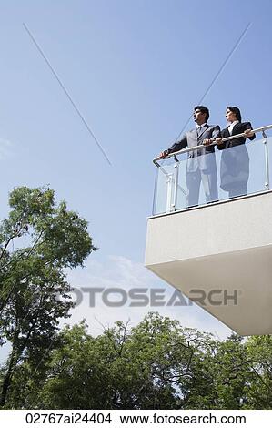 Picture - business associates looking out from balcony. Fotosearch