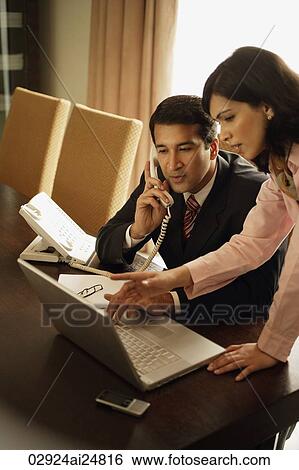 Stock Photograph - business associates meeting, one on phone. Fotosearch