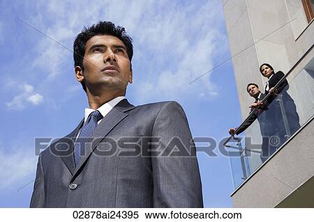 Stock Photography - businessman in foreground, business associates looking down from balcony. Fotosearch