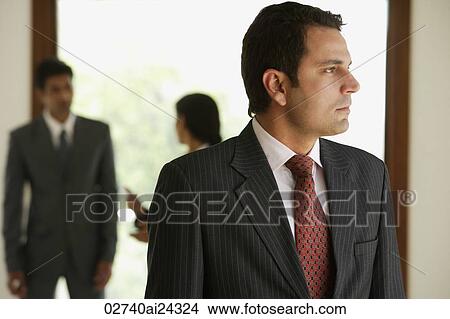 businessman in foreground, two business associates talking in background View Large Photo Image Picture - businessman in foreground, two business associates talking in background. Fotosearch