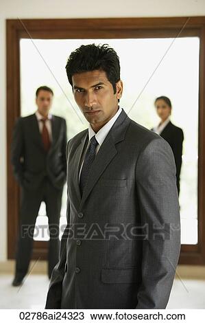 Stock Image - businessman in foreground, two business associates in background. Fotosearch