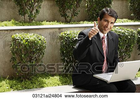 Picture - businessman, laptop computer, thumbs-up, outside. Fotosearch