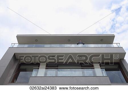 Stock Image - businessman looking over edge of balcony. Fotosearch