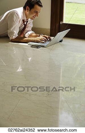 Stock Image - businessman on floor working on computer. Fotosearch