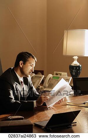 Stock Image - businessman reading documents in office. Fotosearch