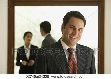 businessman smiling, two business associates talking in background View Large Photo Image Stock Photography - businessman smiling, two business associates talking in background. Fotosearch