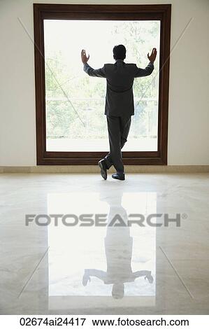 Stock Photo - businessman standing with hands on window. Fotosearch