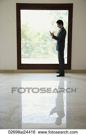 businessman using phone standing next to window View Large Photo Image Stock Photograph - businessman using phone standing next to window. Fotosearch