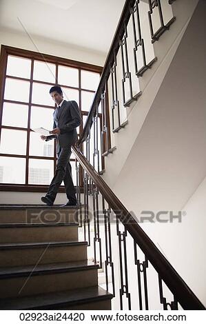 Stock Image - businessman walking down the stairs, documents in hand. Fotosearch