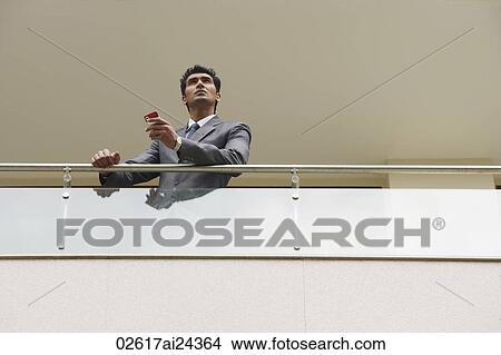 Picture - businessman with mobile phone standing at balcony. Fotosearch