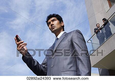 Stock Image - businessman with phone, business associates on balcony. Fotosearch