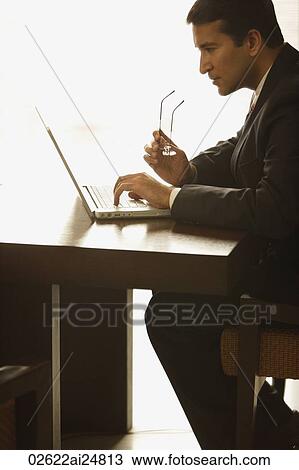 Stock Image - businessman working on laptop computer, glasses. Fotosearch