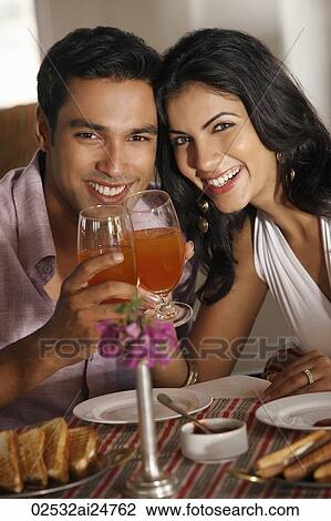Stock Image - couple at restaurant, raising for a toast. Fotosearch
