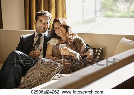 Stock Image - couple on couch holding glasses of wine. Fotosearch