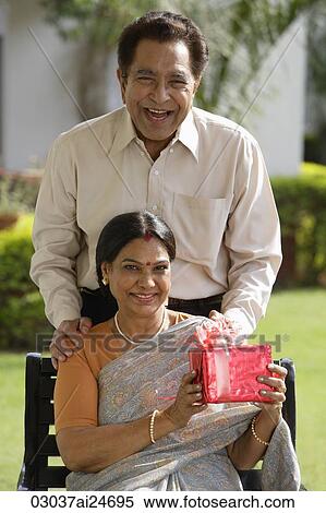 couple posing outdoors for portrait, woman holding gift and wearing sari and bindi View Large Photo Image Stock Photography - couple posing outdoors for portrait, woman holding gift and wearing sari and bindi. Fotosearch