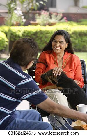 couple sitting outdoors, playing with dog View Large Photo Image Stock Photography - couple sitting outdoors, playing with dog. Fotosearch