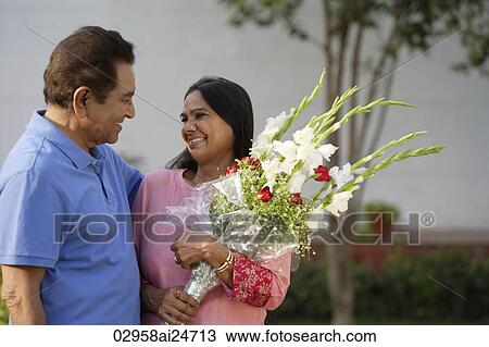 Stock Image - couple smiling at each other, woman with bouquet. Fotosearch