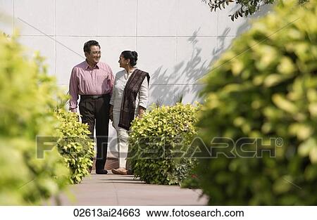 Stock Image - couple standing in garden path, woman wearing salwar kameez and shawl. Fotosearch