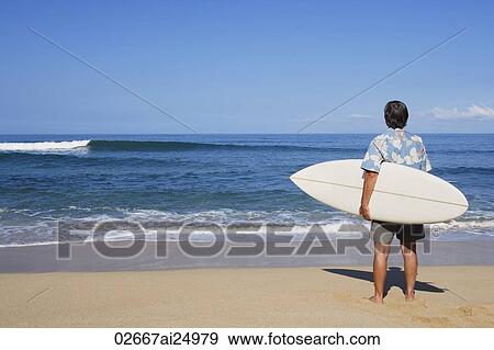 Stock Photo - man holding surf board on beach. Fotosearch