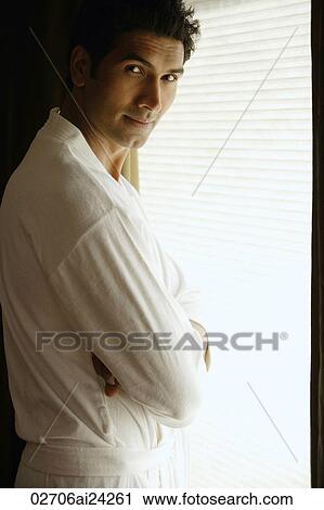 Stock Image - man in robe, standing near window. Fotosearch