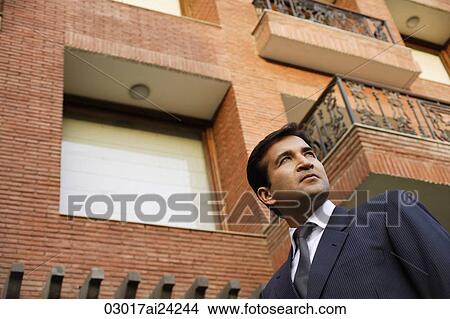 Picture - man in suit, standing in front of home. Fotosearch