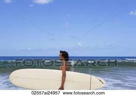 Stock Photo - man looking out to sea, holding surf board. Fotosearch