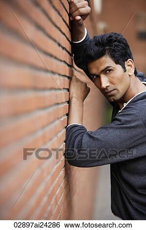 Stock Photograph - man posing against brick wall. Fotosearch