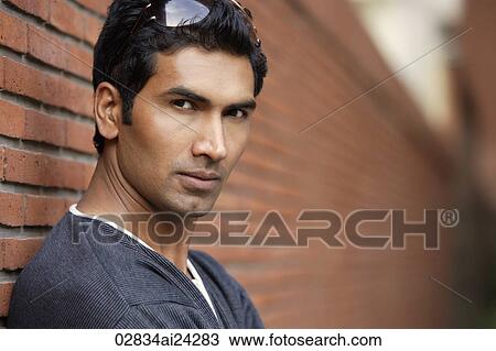 Stock Image - man standing against brick wall. Fotosearch