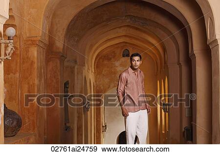 Stock Photo - man standing in arched hallway. Fotosearch