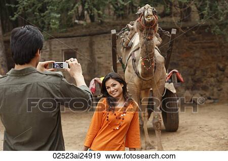 Stock Photo - man taking photo of woman in front of camel. Fotosearch