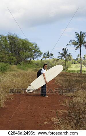 Stock Photography - man walking on trail with surf board. Fotosearch