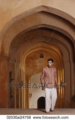 Stock Photo - man walking up arched hallway. Fotosearch