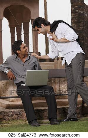 men talking outside, one working at laptop computer View Large Photo Image Stock Image - men talking outside, one working at laptop computer. Fotosearch