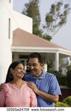 Stock Photo - smiling couple standing in front of house. Fotosearch