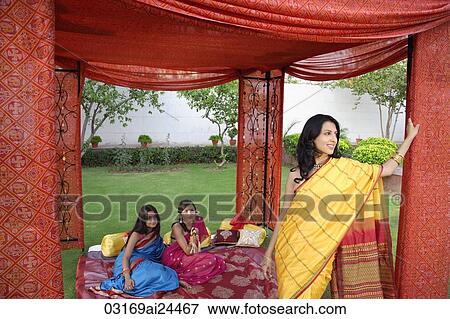 Stock Photo - three young women wearing saris, in red tent. Fotosearch