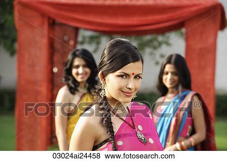 Stock Photo - three young women wearing saris, in front of tent. Fotosearch