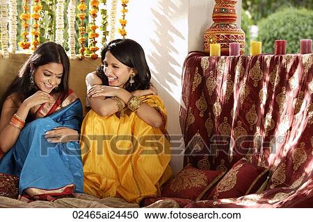 Stock Image - two young women chatting, wearing saris. Fotosearch