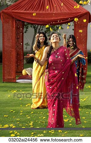 two young women throwing petals on another woman, all three wearing saris standing in front of tent View Large Photo Image Stock Photograph - two young women throwing petals on another woman, all three wearing saris standing in front of tent. Fotosearch