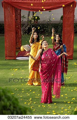 two young women throwing petals on another woman, all three wearing saris standing in front of tent View Large Photo Image Stock Photography - two young women throwing petals on another woman, all three wearing saris standing in front of tent. Fotosearch