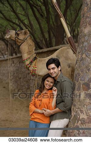 Stock Photo - young couple embracing, camel at background. Fotosearch