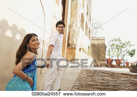 young couple holding hands walking up a slope, woman in sari View Large Photo Image Stock Photo - young couple holding hands walking up a slope, woman in sari. Fotosearch