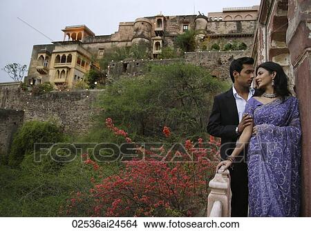 Picture - young couple standing on balcony, woman in sari. Fotosearch