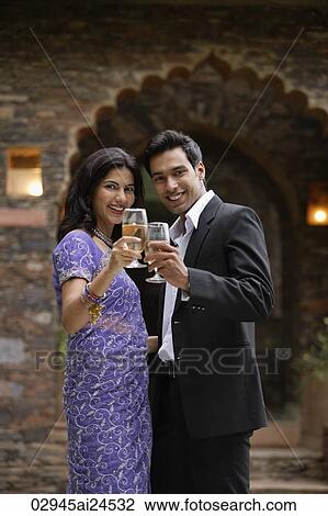 Stock Image - young couple with glass of wine, toasting, woman in sari. Fotosearch